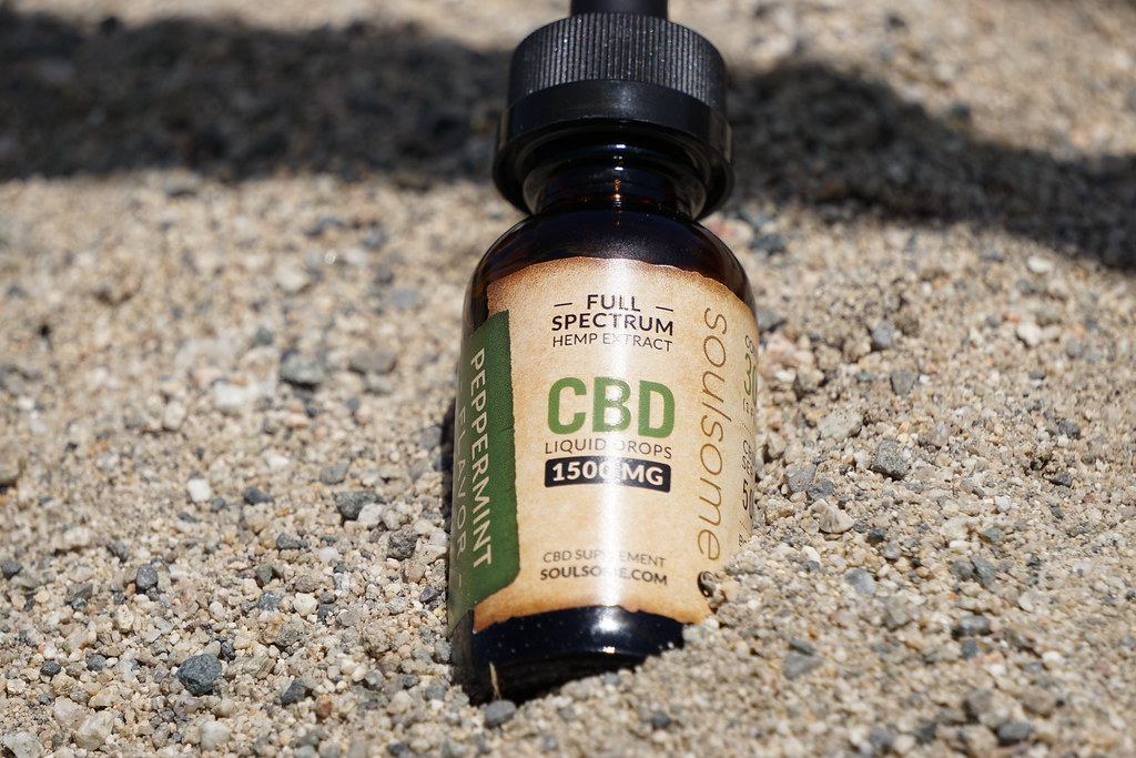 Soulsome full spectrum CBD peppermint liquid drops bottle resting on sand